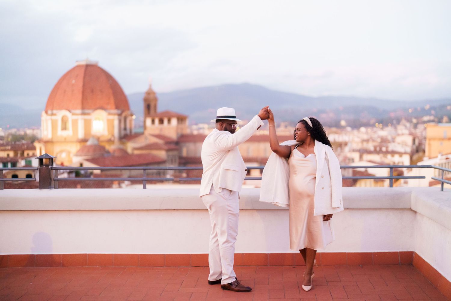 Couple dancing on rooftop in Florence Italy with the Duomo cathedral dome and city skyline at dusk.