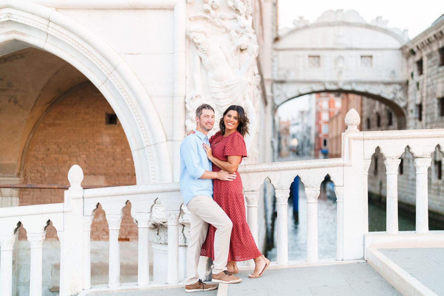 Couple embracing on a Venetian bridge near the Bridge of Sighs in Venice, Italy, with canal views.