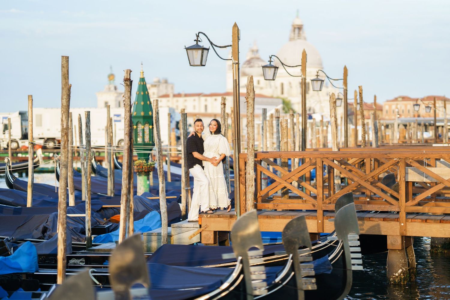 Couple embracing on a gondola dock in Venice, Italy, with iconic Santa Maria della Salute basilica in the background.