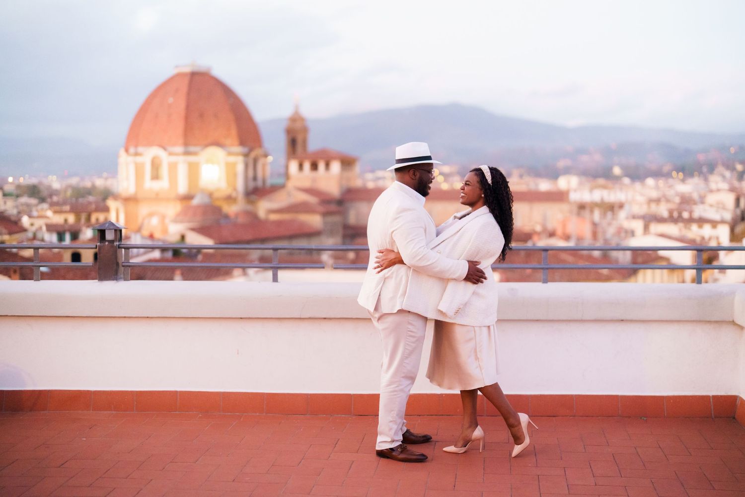 Couple kissing on rooftop terrace in Florence Italy with the Duomo cathedral dome in the background.