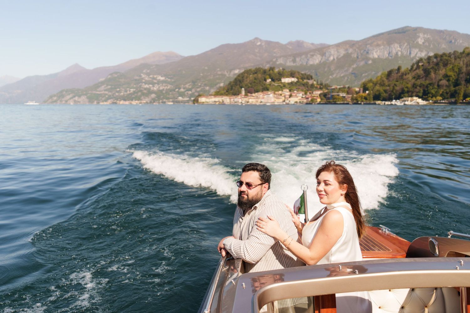 Couple enjoying a scenic boat ride on Lake Como with mountain views and blue waters.