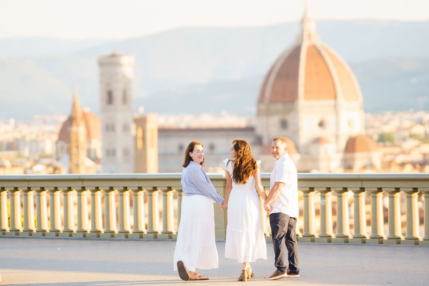 A romantic couple poses against the stunning backdrop of Florence, Italy with the iconic Duomo cathedral visible in the distance.
