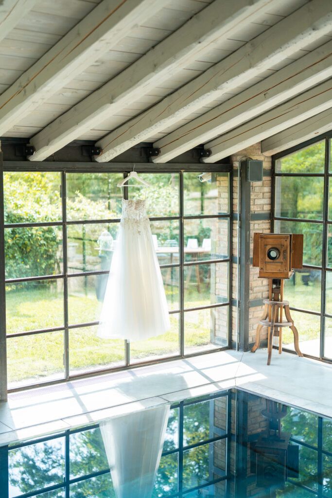 Modern indoor swimming pool with floor-to-ceiling windows and exposed wooden beams offering natural light and garden views.