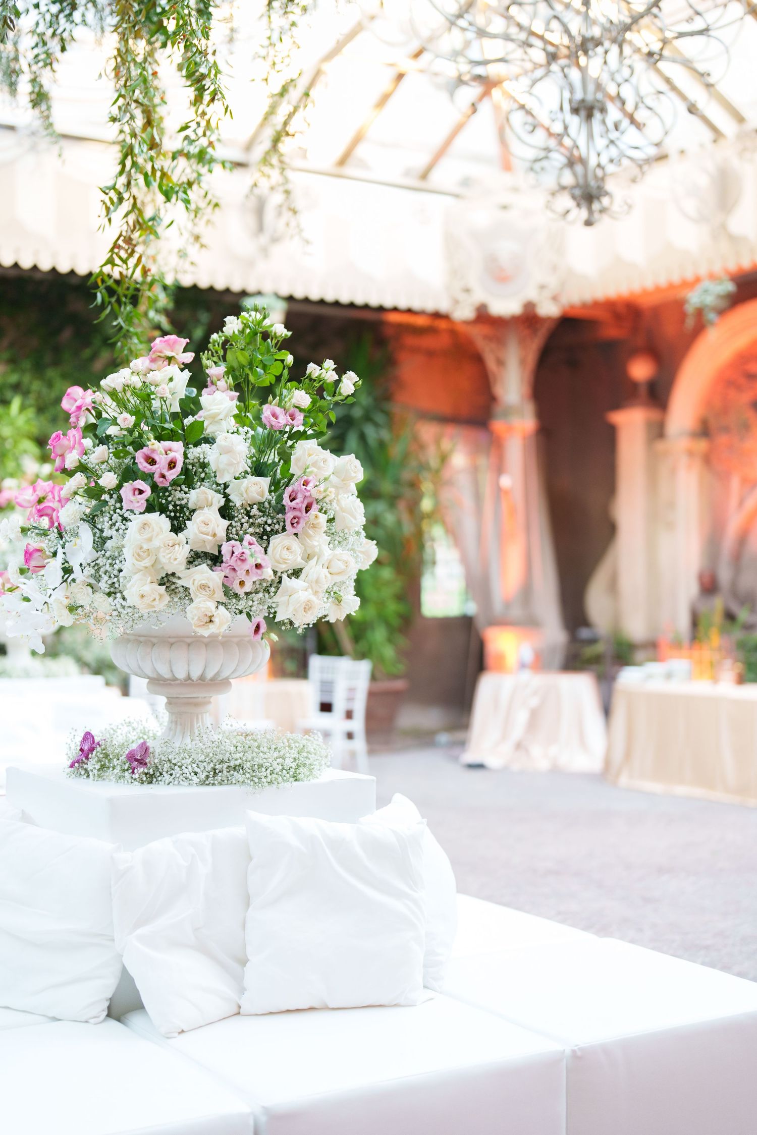 Elegant white floral centerpieces with pink accents displayed on tables at an outdoor wedding venue.