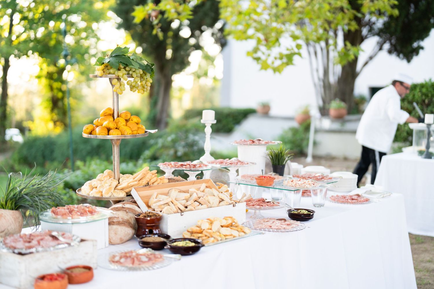 An elegant outdoor wedding buffet spread with tiered displays and various appetizers.