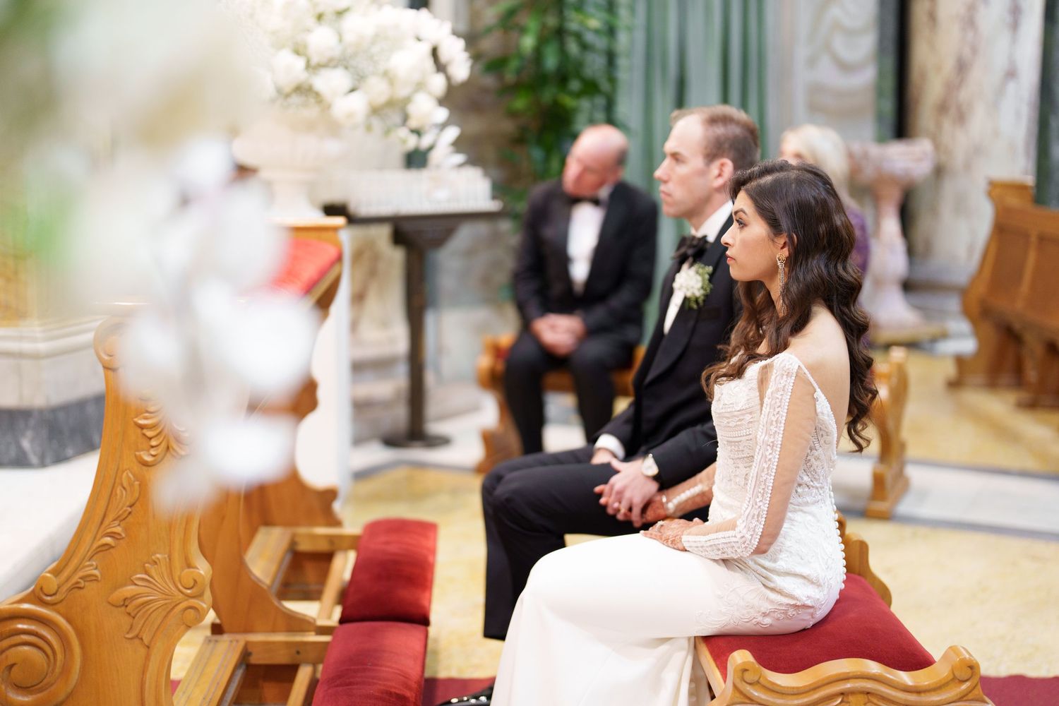 Formal gathering in church with ornate marble columns and wooden pews.