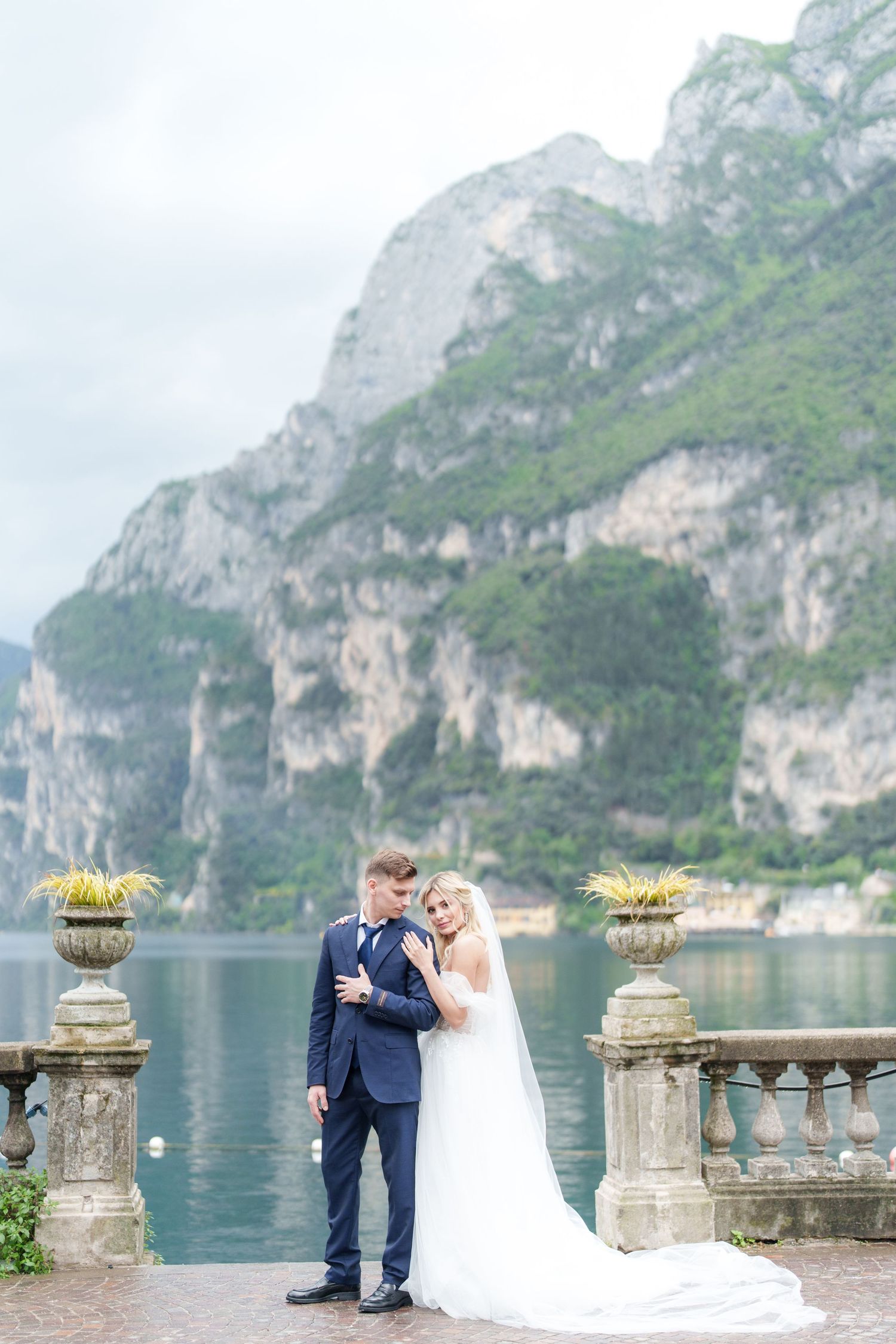 A romantic wedding photo series captured at Lake Garda in Italy with dramatic mountain cliffs and turquoise waters.