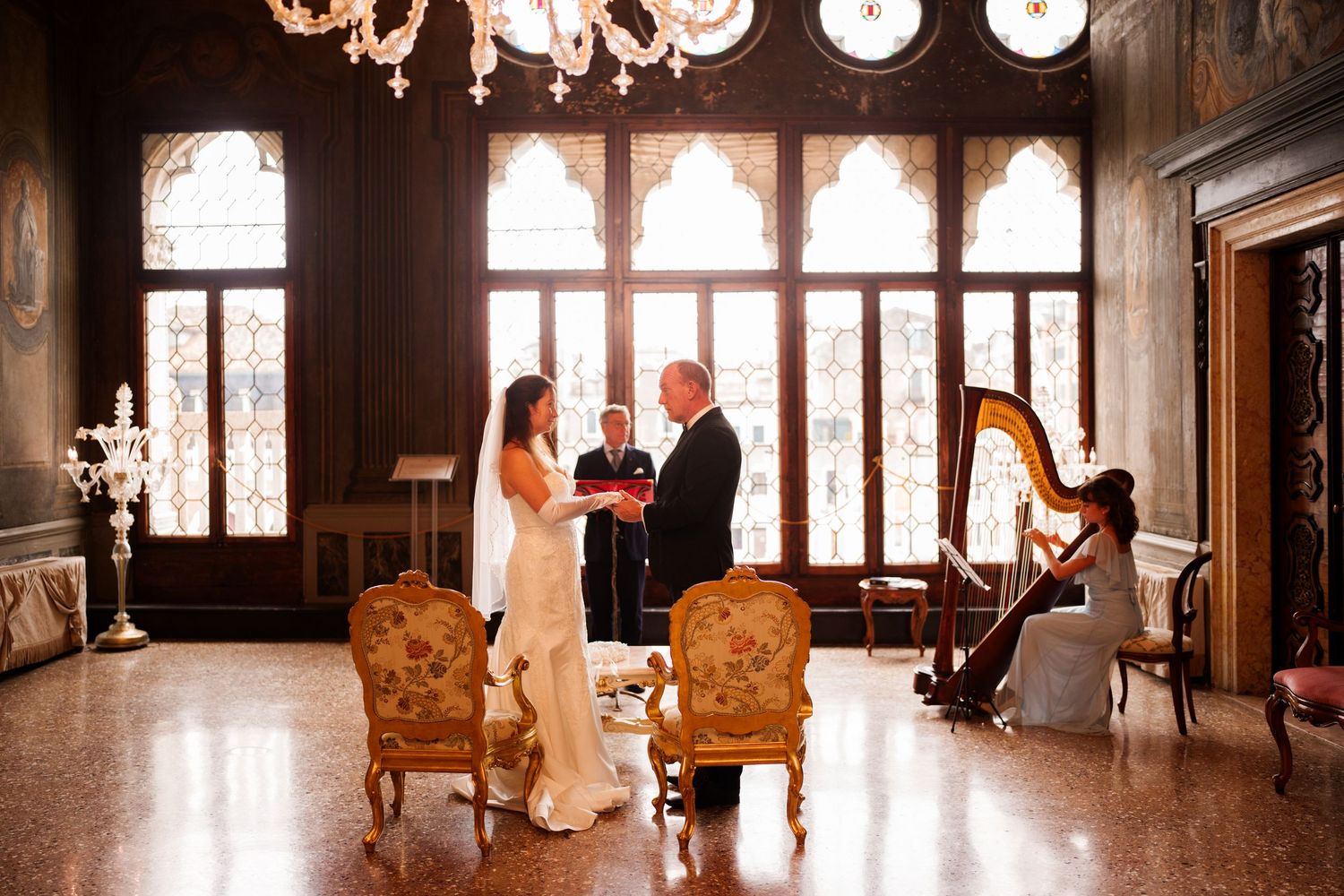 Elegant wedding photo session in a luxurious vintage room with ornate furniture and grand windows.