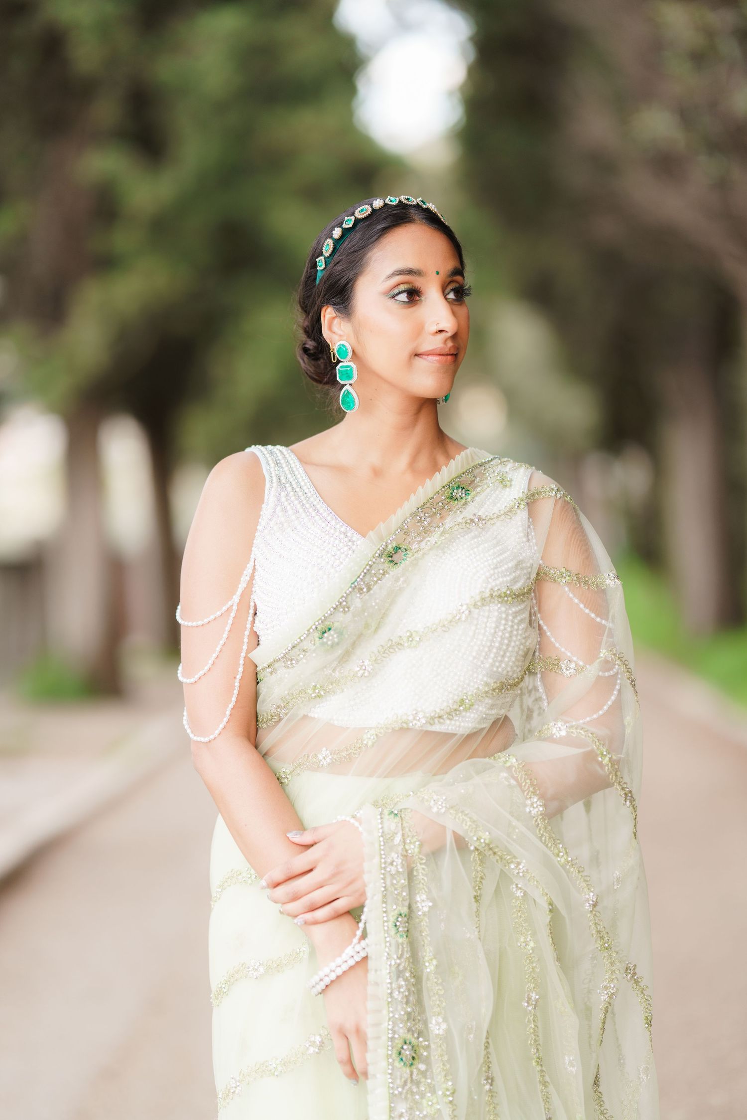 A series of photos showing a woman in an elegant cream-colored sari with pearl draping details posing outdoors.