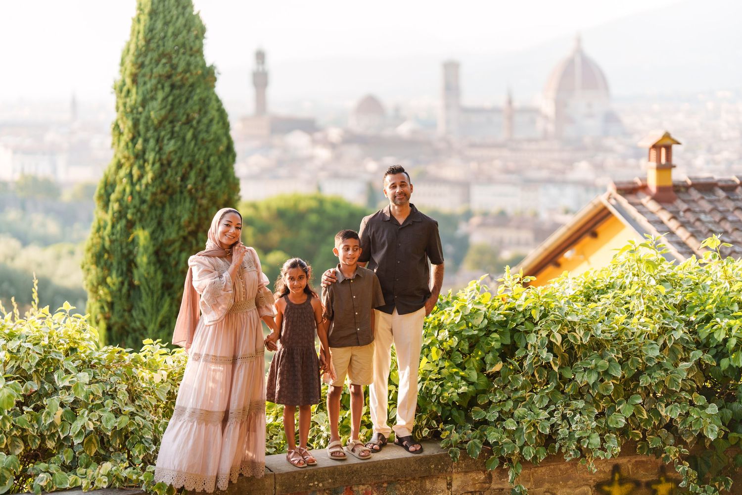 Family of four posing with Florence cathedral skyline backdrop at golden hour in Italy.