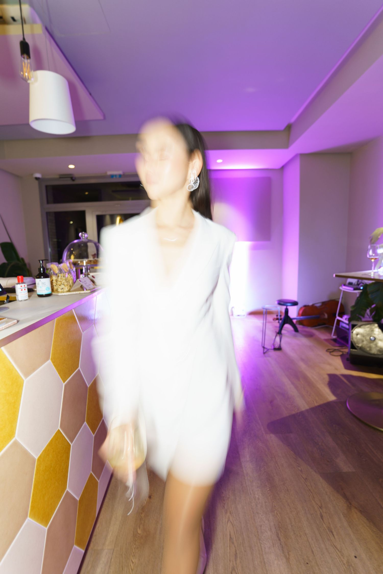 Blurred motion shot of a woman in white dress at a purple-lit bar venue.