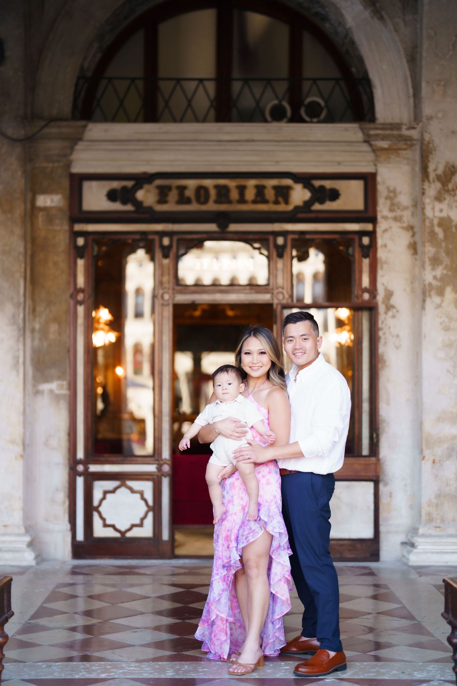 A smiling family poses with their baby in front of Caffe Florian in Venice, Italy.