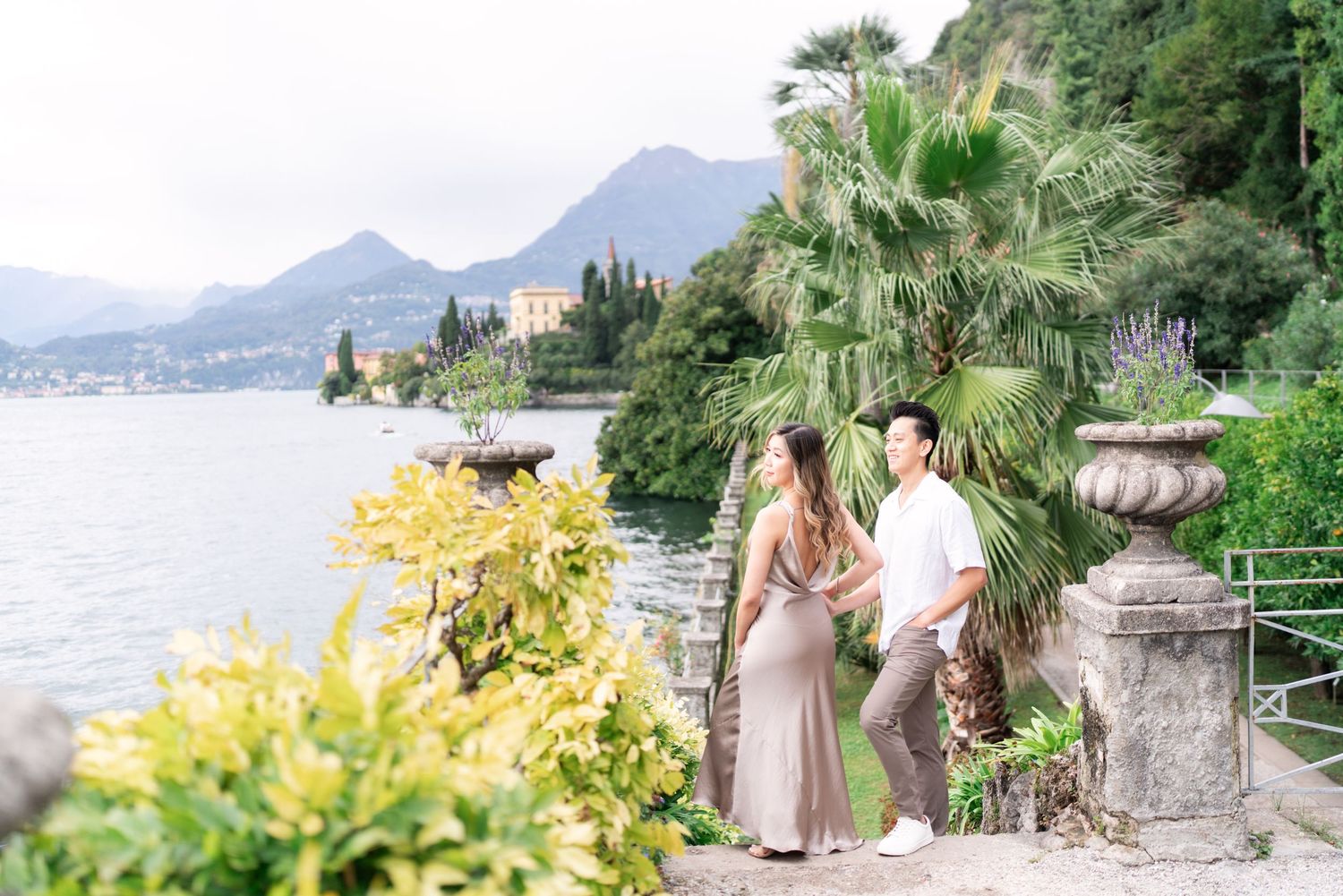Scenic lakeside wedding photography session with mountains and palm trees along Lake Como in Italy.