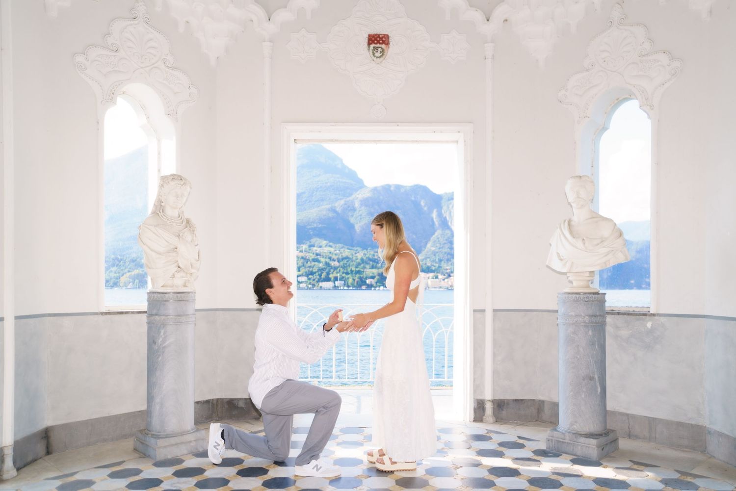 A person in white clothing performs yoga poses in a bright, minimalist room with arched windows overlooking mountains.