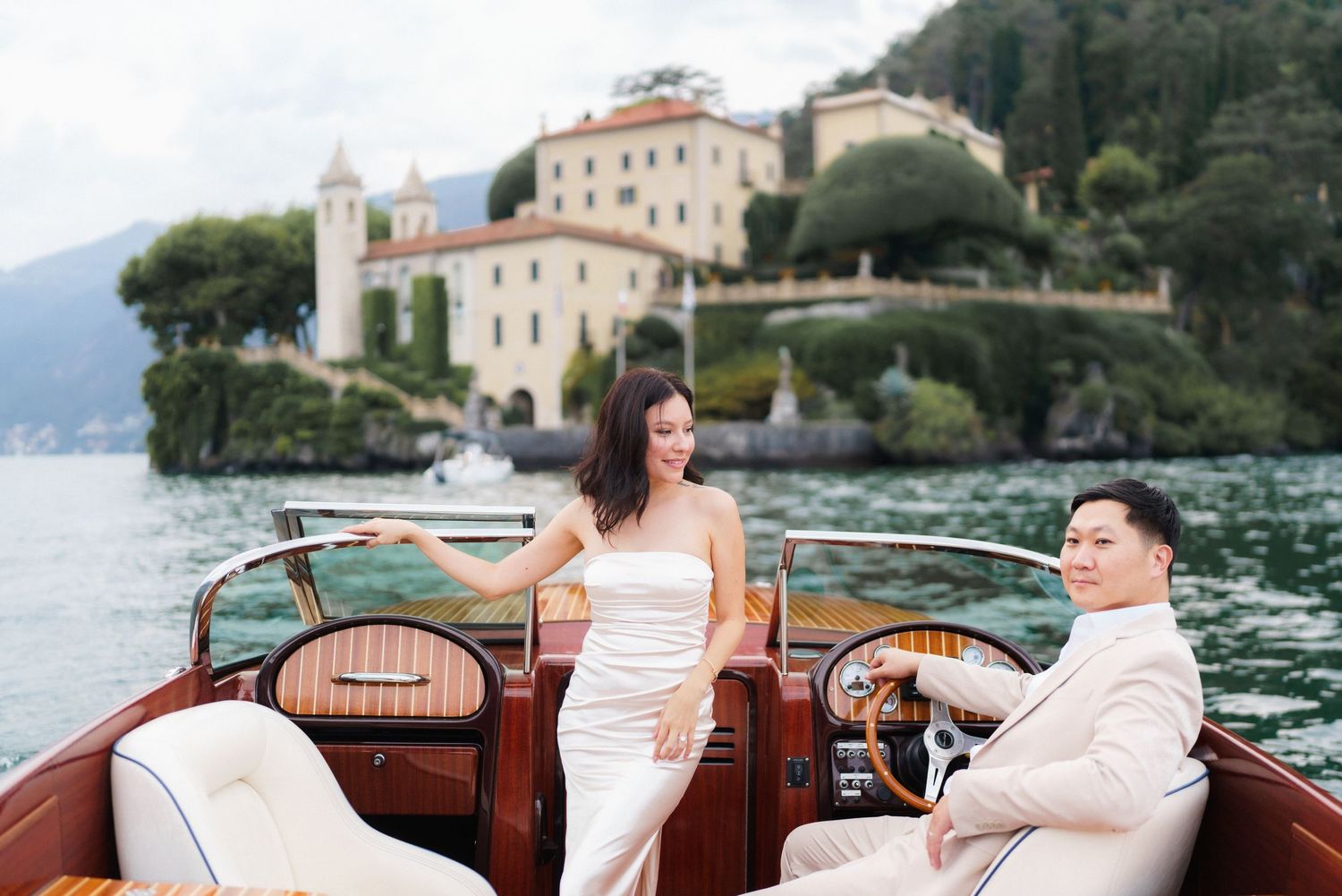 Couple enjoying a romantic boat ride along Lake Como in Italy with scenic villa views in the background.