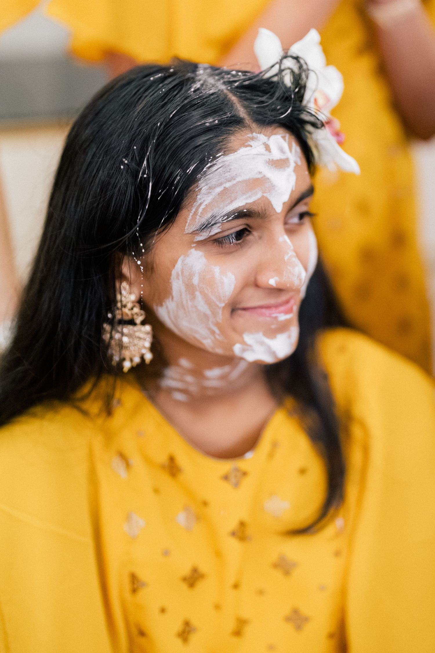 Person in bright yellow clothing with white face decorations smiling at the camera.