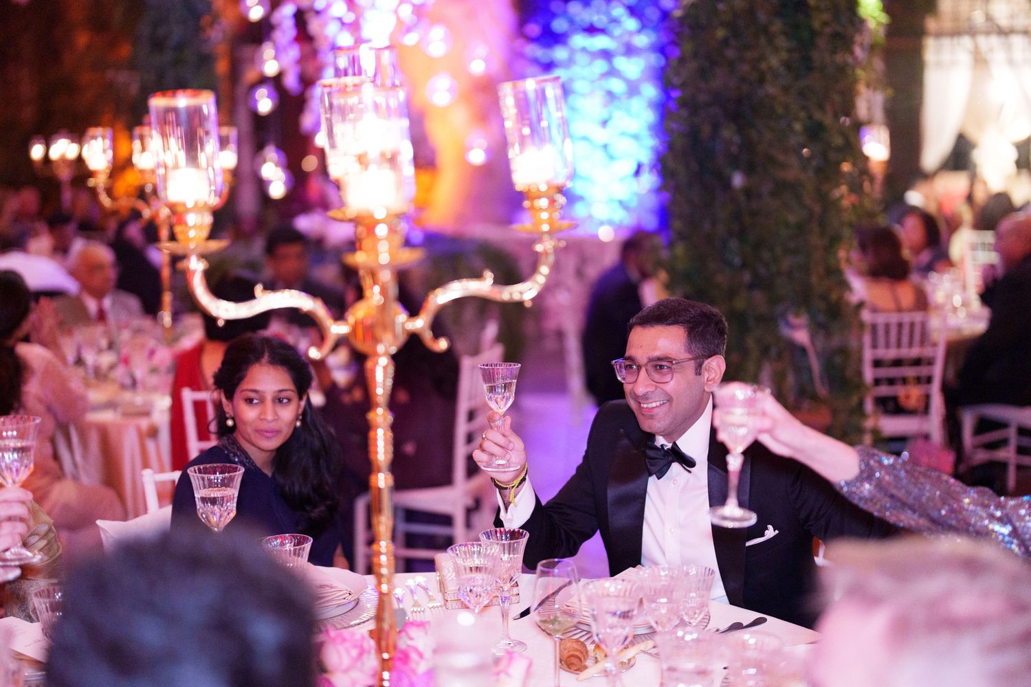 Wedding reception venue decorated with dramatic purple and blue lighting creating an intimate atmosphere.