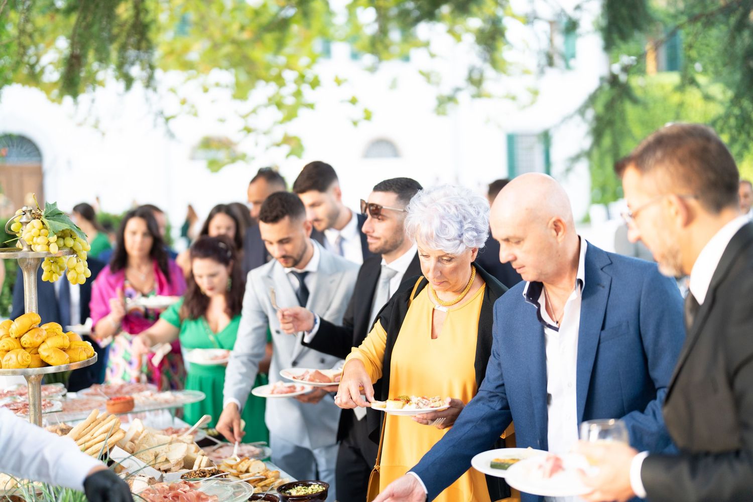 Wedding guests enjoy a catered buffet dinner at elegantly decorated outdoor tables.