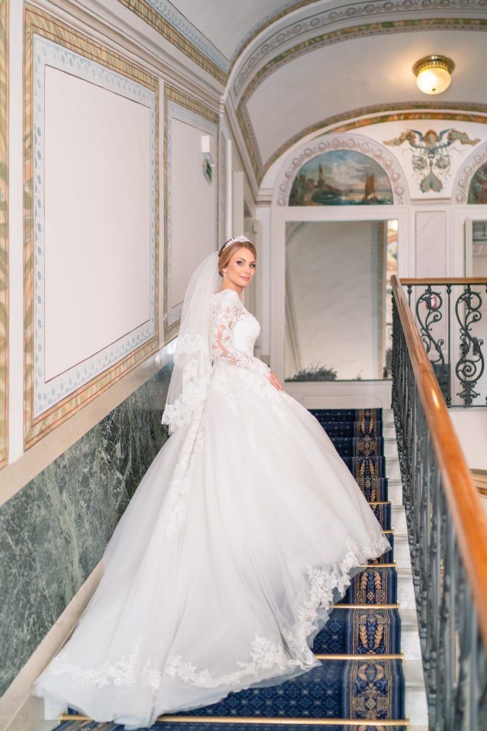 Elegant marble staircase with ornate details showcasing a flowing white wedding gown.