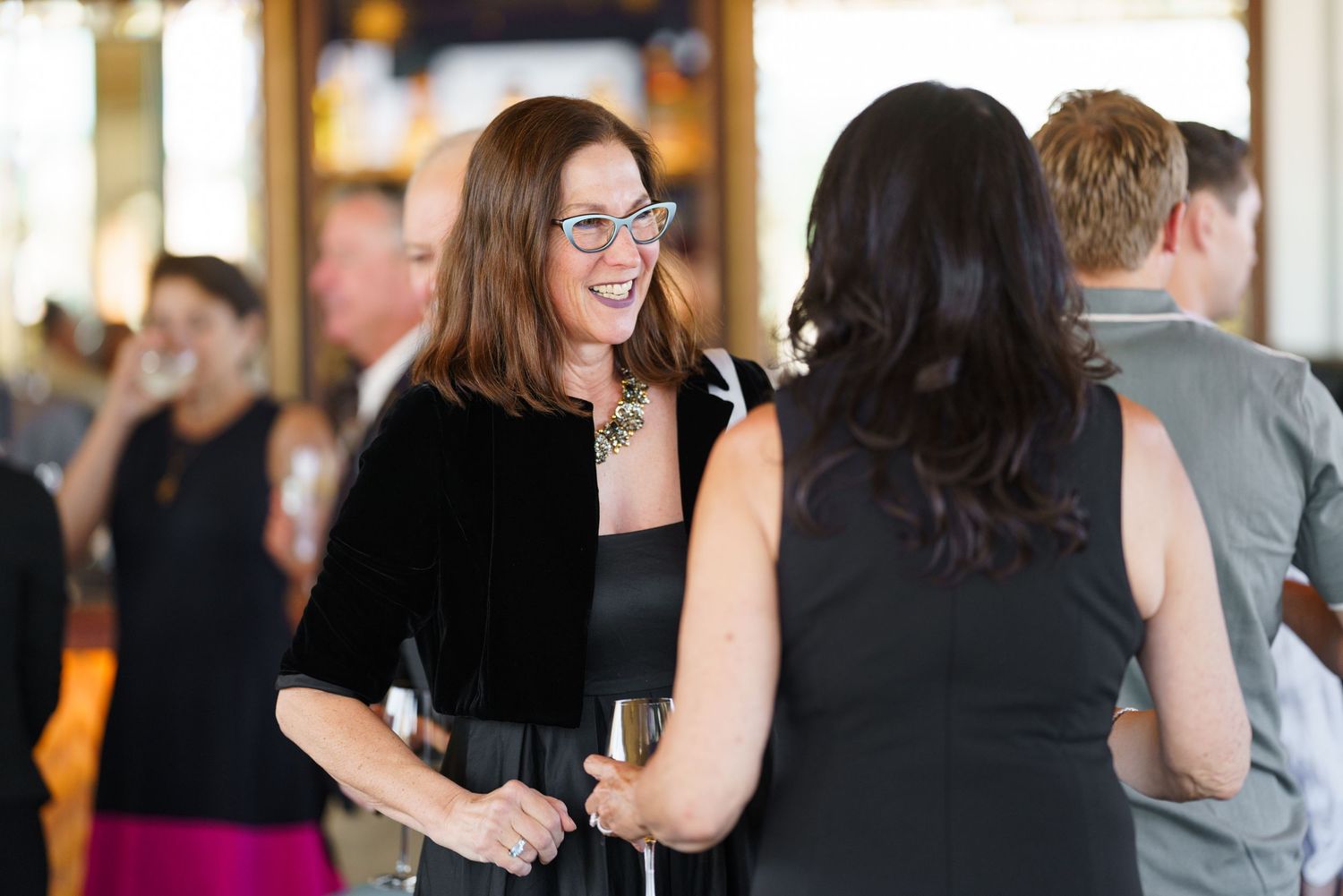 Two people engaged in animated conversation at an indoor social gathering.