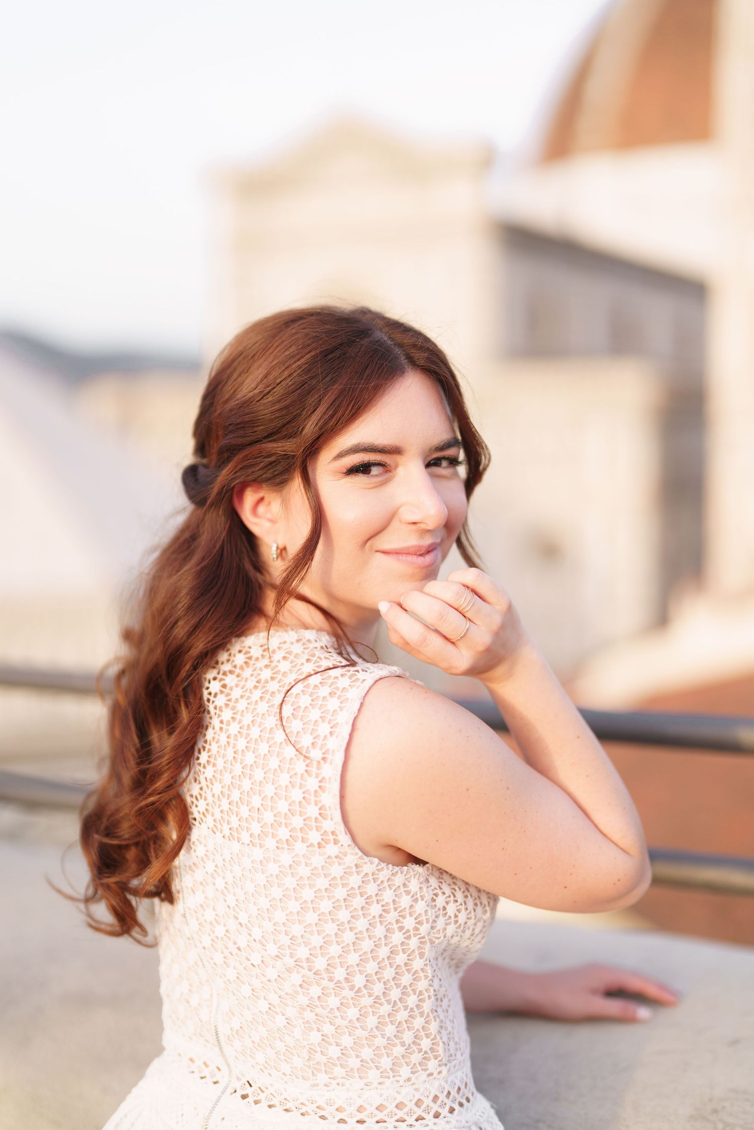 A woman in a white lace top poses outdoors in a series of candid portrait shots with warm lighting.