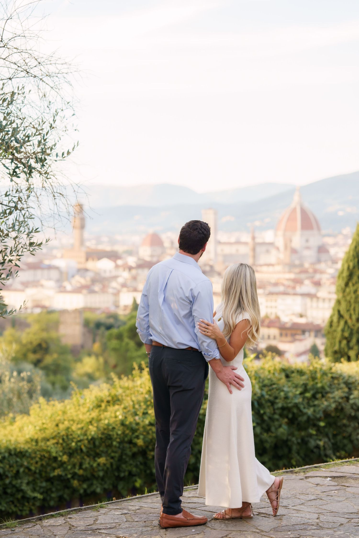 A couple admires the stunning cityscape of Florence, Italy with its iconic Duomo cathedral from a scenic hilltop viewpoint.