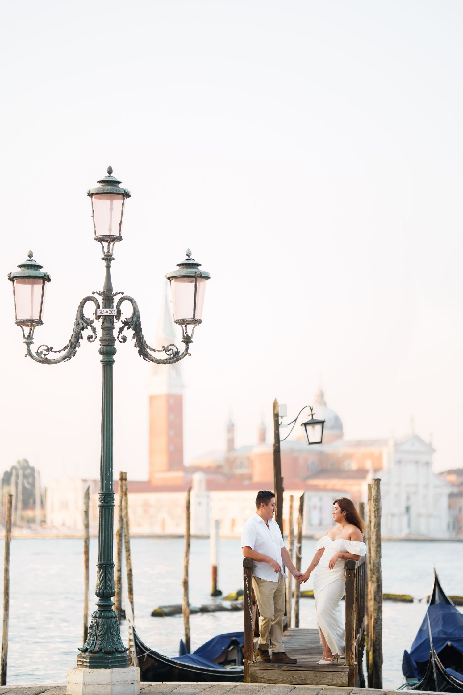 Romantic evening scene in Venice with ornate street lamps and gondolas along the waterfront at sunset.