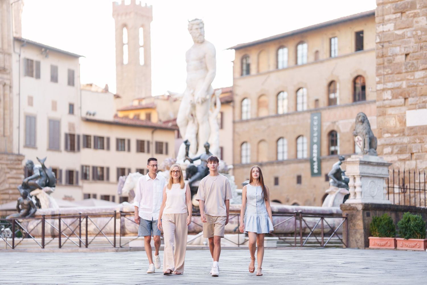 Group walking through historic streets of Florence with Palazzo Vecchio tower visible in background.