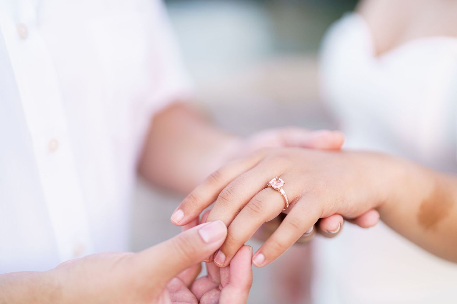 Close-up of hands exchanging wedding rings during a ceremony with soft focus and natural lighting.