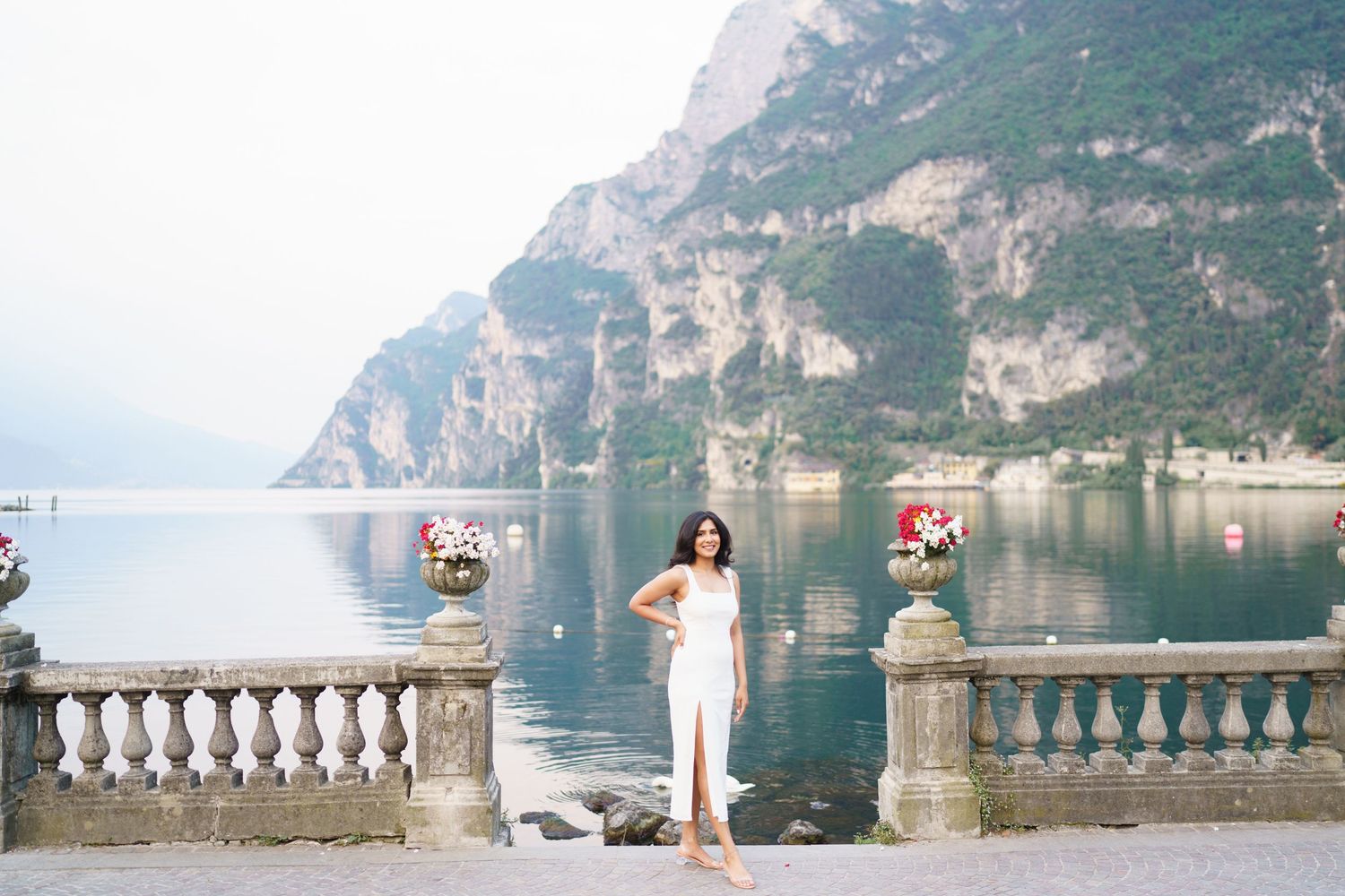 Scenic mountain lake panorama with stone balustrade overlooking calm waters and dramatic cliffs in Italy.