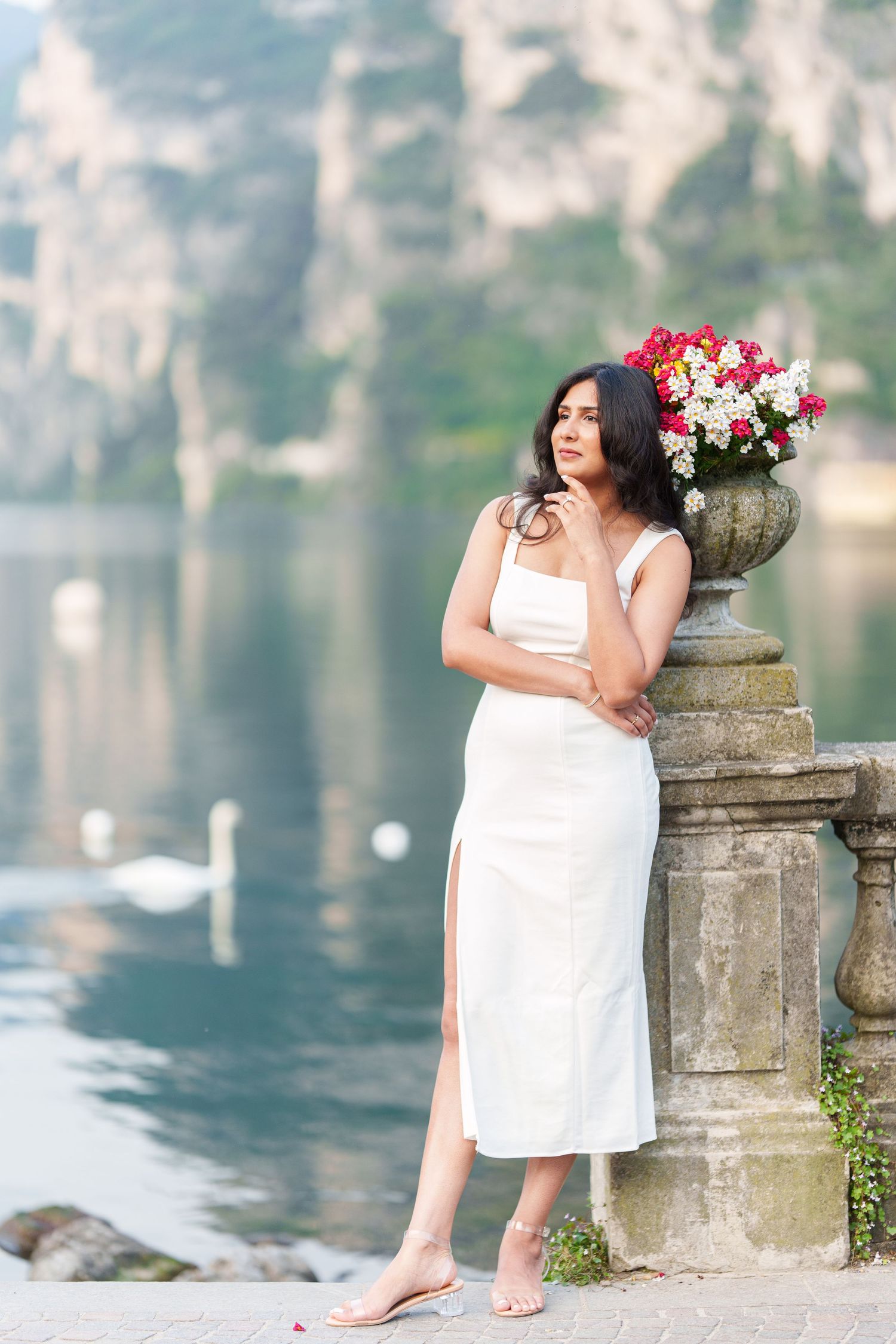 A series of artistic maternity photos taken at a lakeside stone balustrade with soft blurred water in the background.