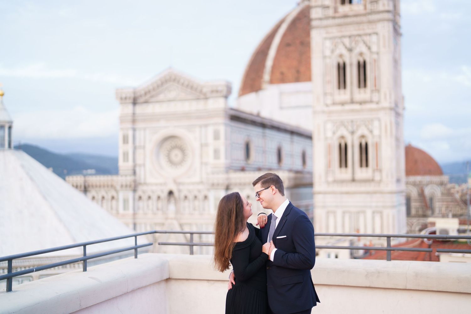 Romantic couple embraces on a terrace overlooking the historic Florence Cathedral and Duomo in Italy.