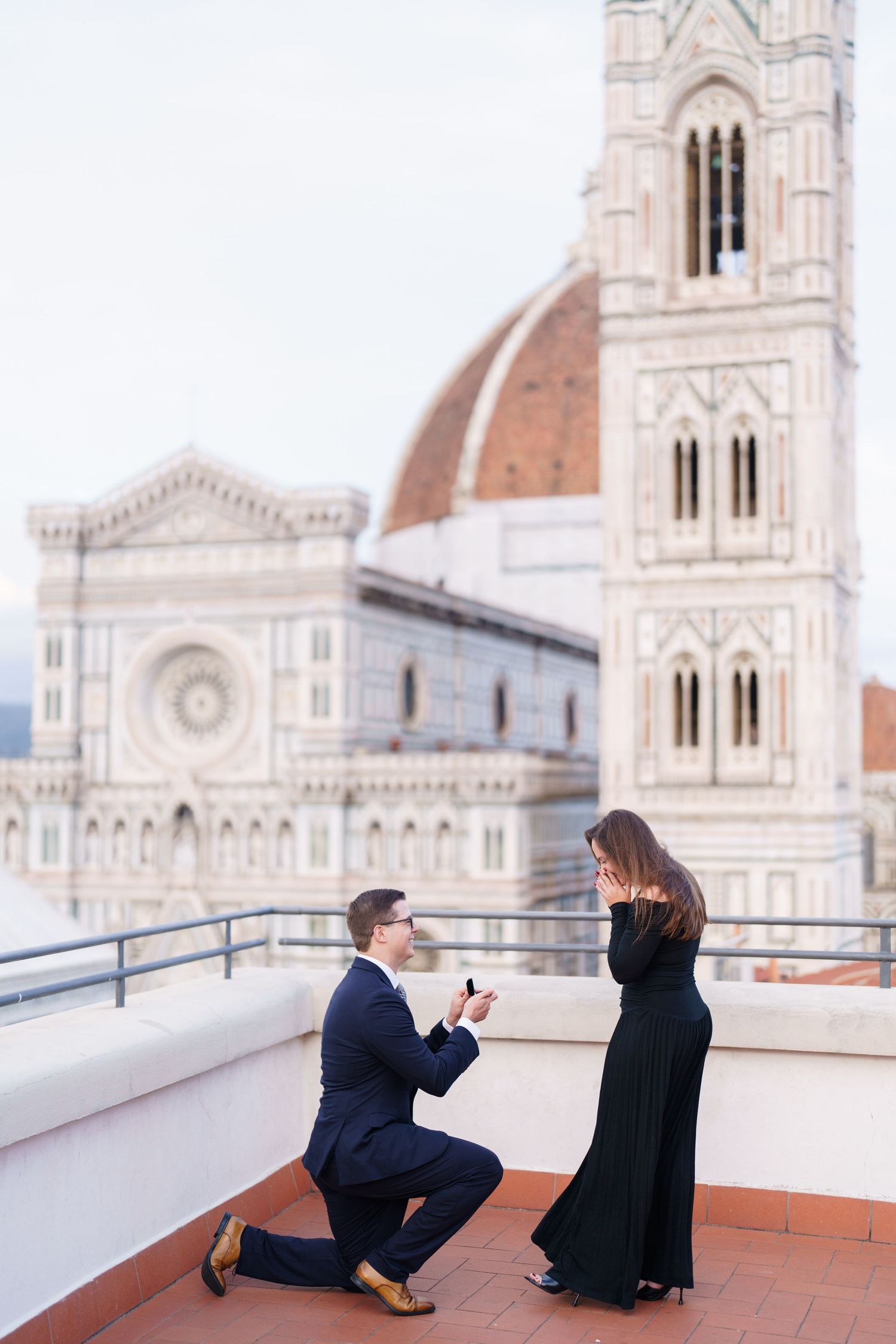 Two people share a romantic moment on a rooftop terrace with Florence Cathedral's iconic dome in the background.
