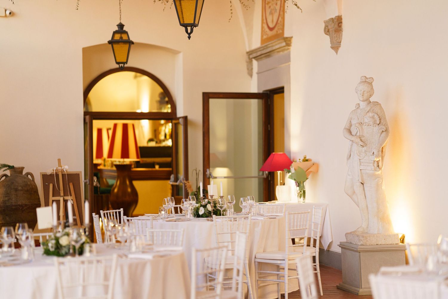 Elegant wedding reception tables set with white linens and decorative candles in a classic indoor venue.
