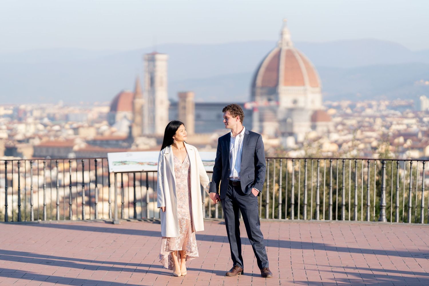 A couple shares romantic moments at a scenic overlook in Florence, Italy with the city's iconic dome in the background.