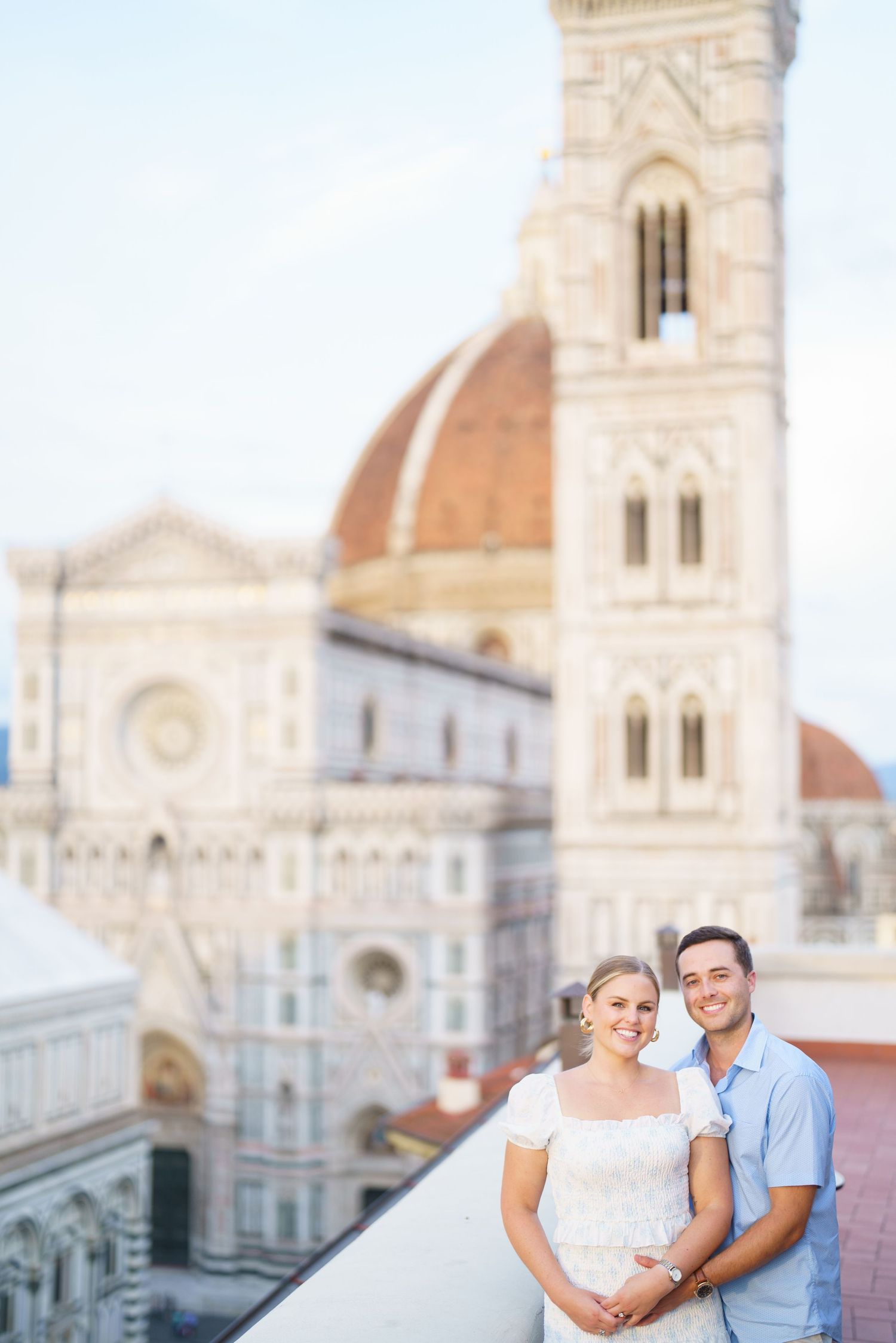 A couple shares romantic moments in Florence, Italy with the historic Duomo cathedral visible in the background.