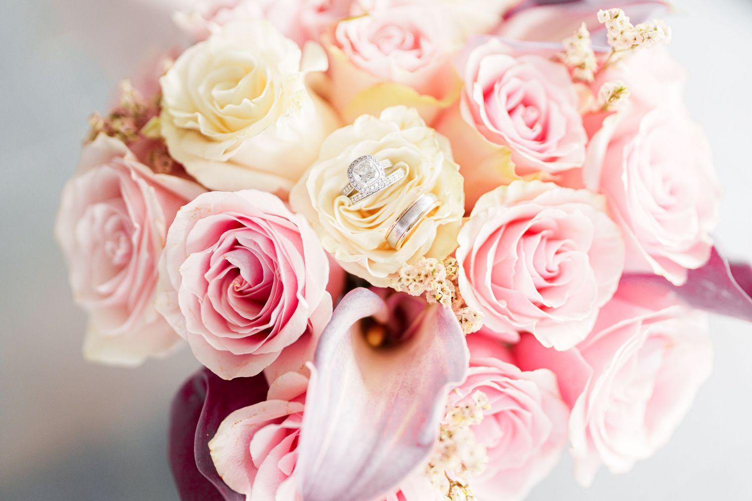 Pink rose bouquet with wedding rings nestled among blooms, perfect for a romantic bridal arrangement.