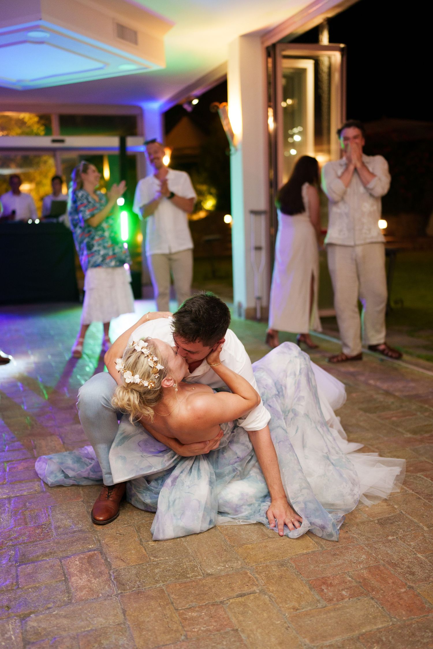 Bride and groom share a romantic dip kiss on the dance floor during their outdoor wedding reception at night.