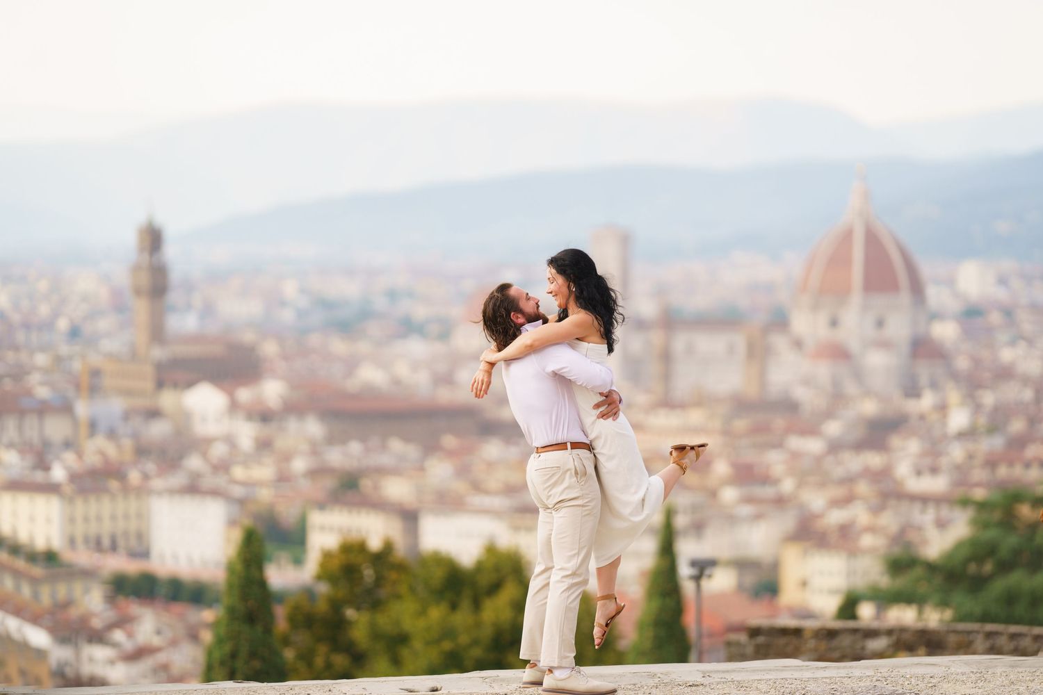 Romantic couple embraces while enjoying panoramic views of Florence, Italy from Piazzale Michelangelo viewpoint.
