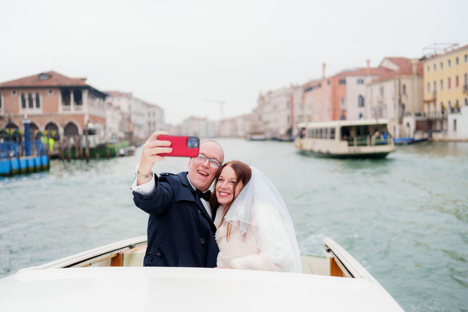 A romantic wedding couple rides in a traditional wooden gondola along Venice's iconic Grand Canal waterways.