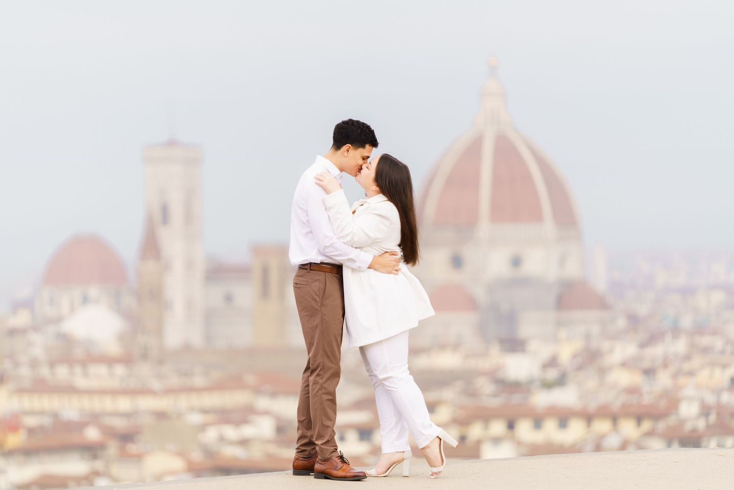 Couple embracing with Florence Cathedral dome in background.