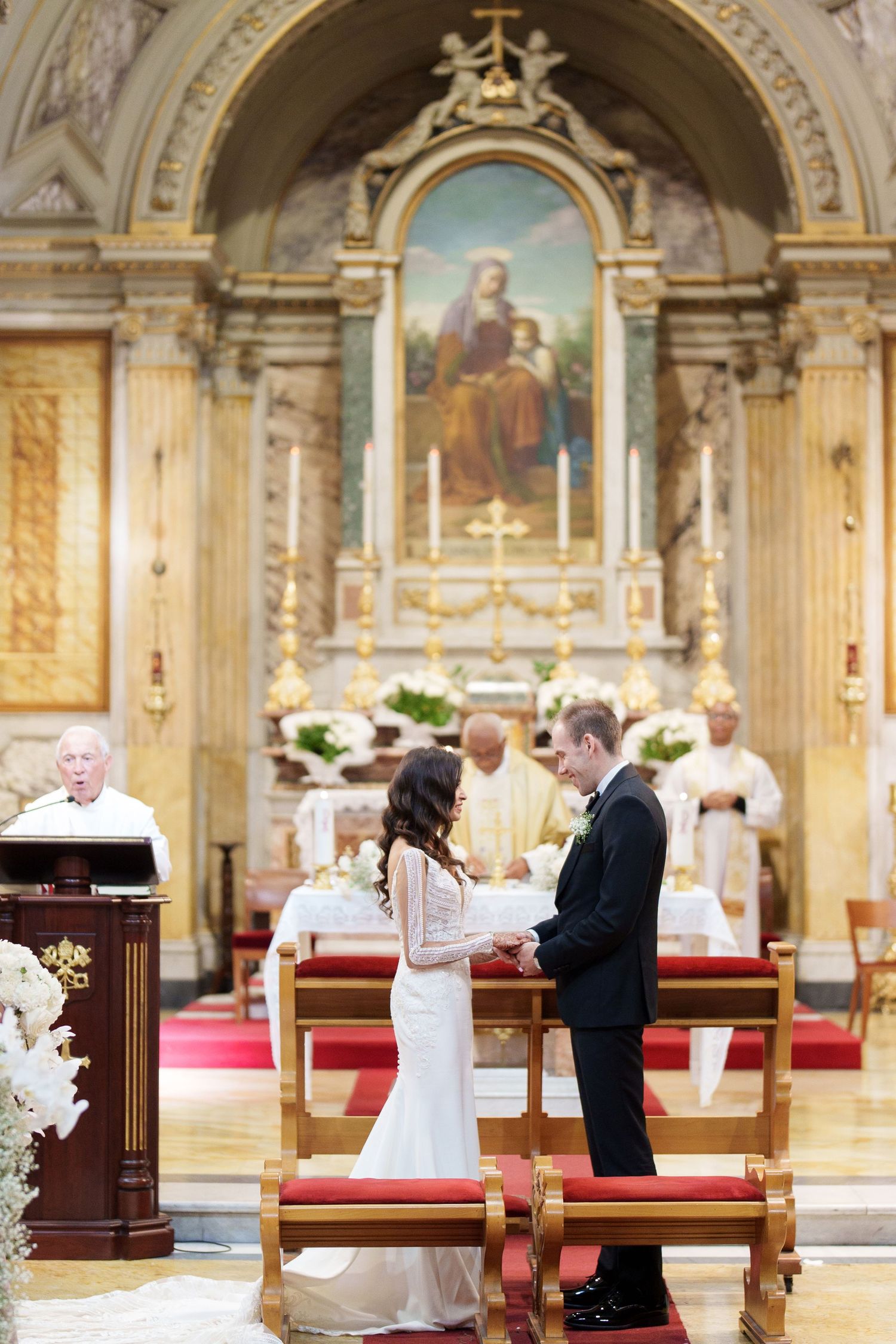 A traditional Catholic wedding ceremony taking place in an ornate church with religious artwork and golden details.