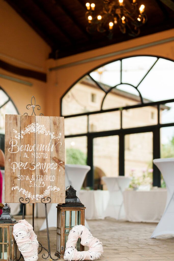 Rustic wooden signs with white text displayed at wedding reception with elegant lighting.