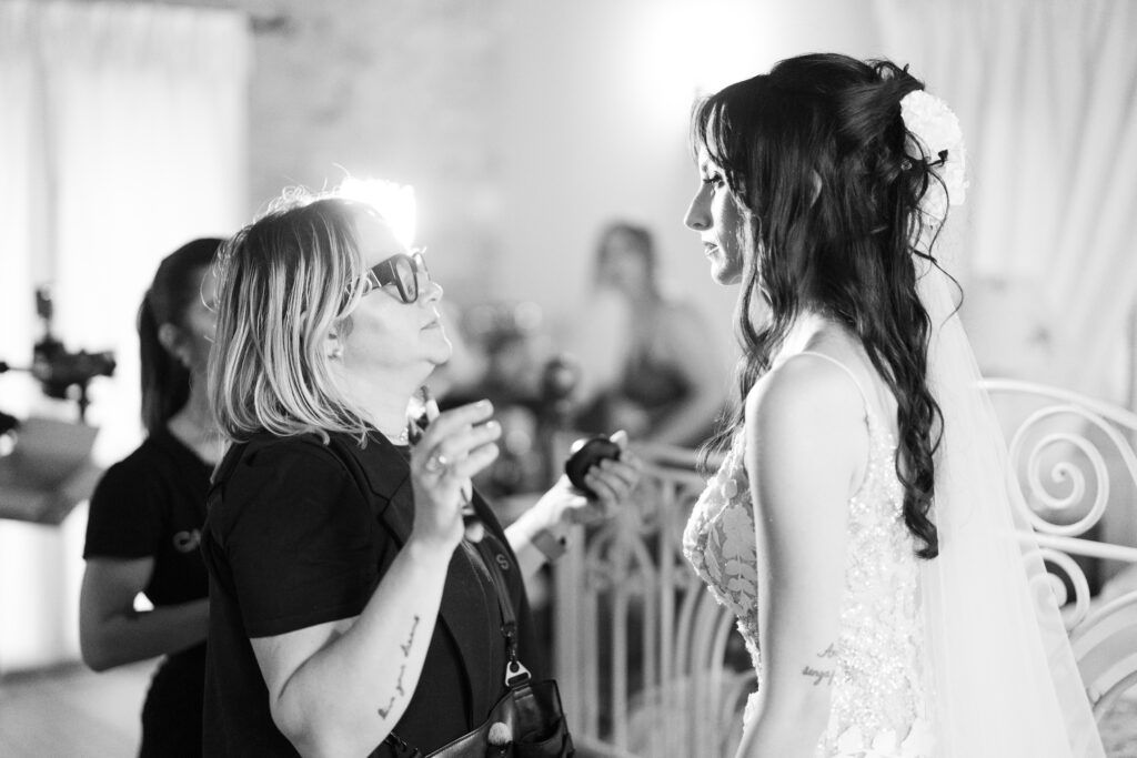 Black and white candid shots of wedding preparations with bridesmaids helping the bride.