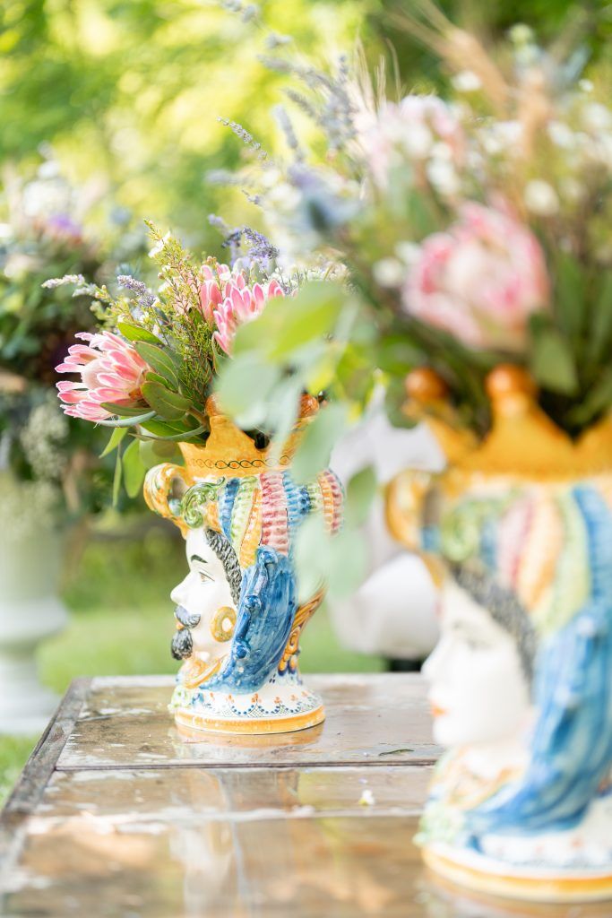 Vintage blue and white decorative vases with pink floral arrangements on rustic wooden surfaces.