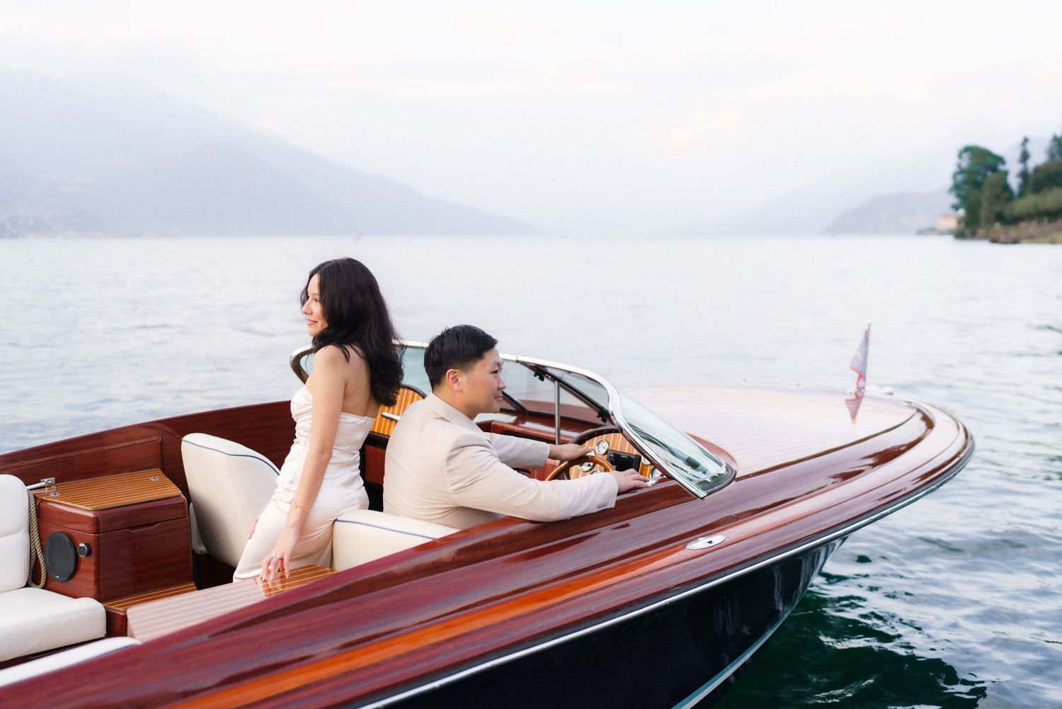 A classic wooden speedboat glides across calm waters with its polished mahogany deck gleaming in the sunlight.