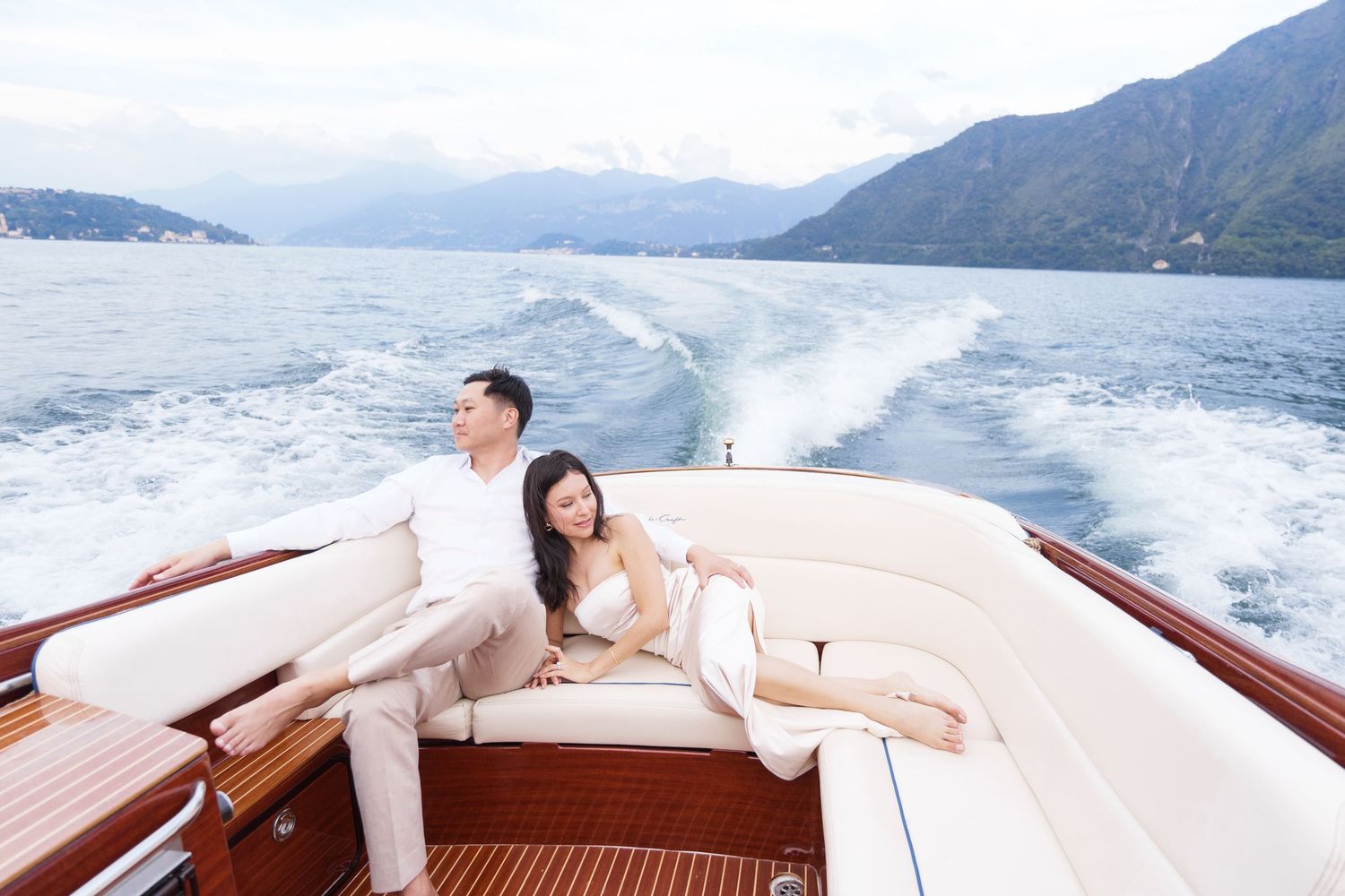 Luxury wooden boat cruising through pristine mountain lake waters creating a white wake on a clear summer day.
