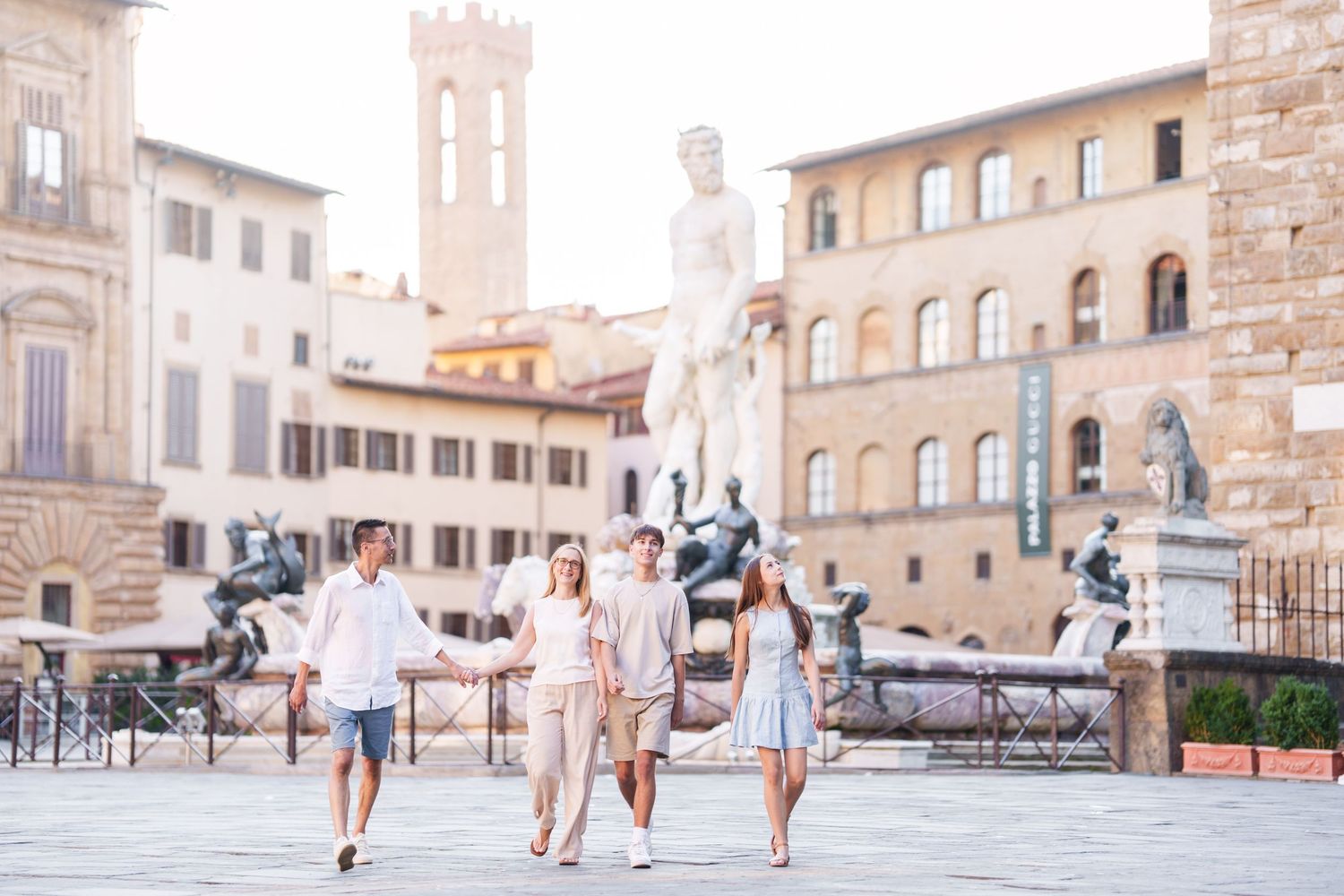 People walking in a historic Italian square surrounded by medieval stone buildings and architecture.