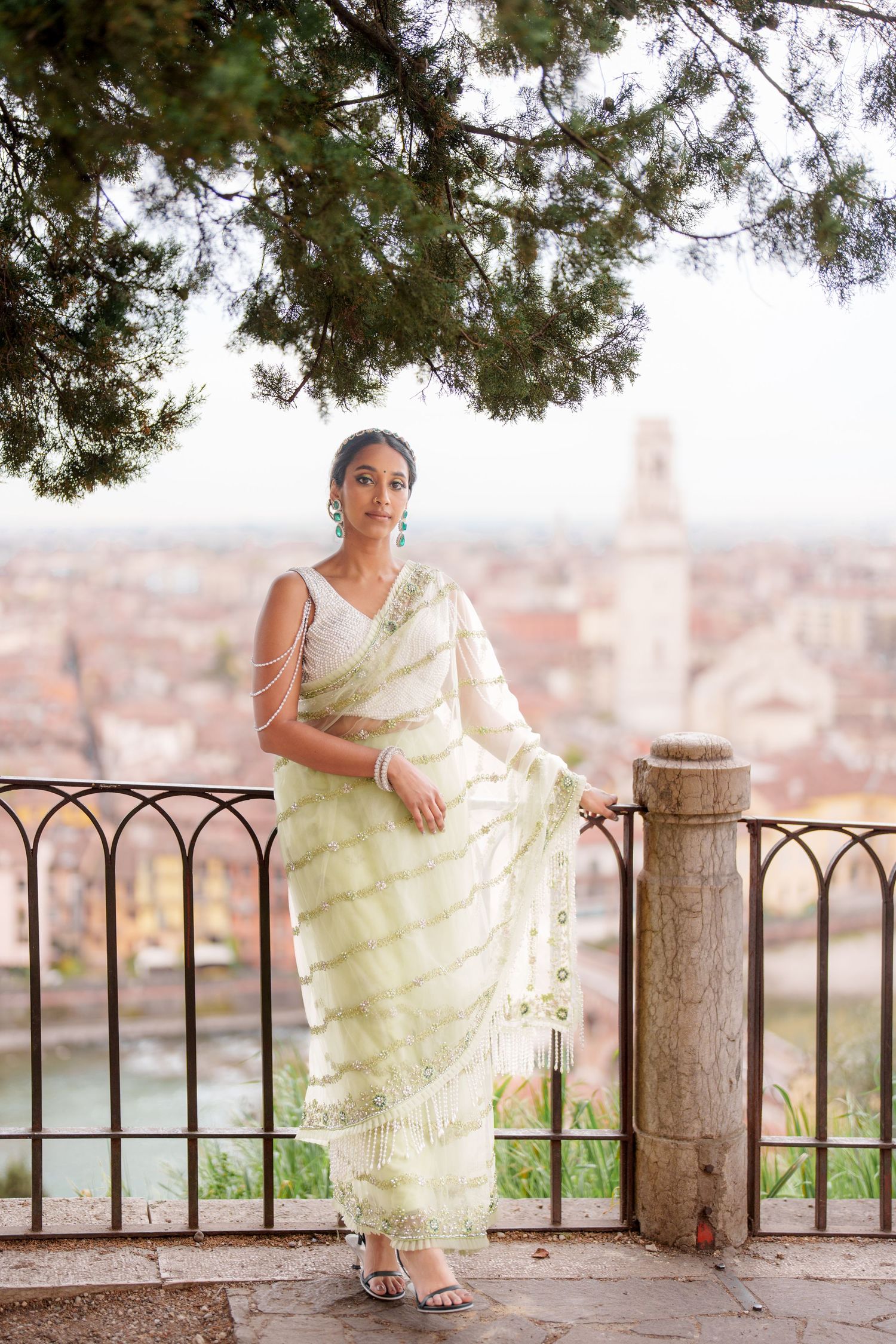 A series of four photos showing a person in a light-colored dress sitting on a stone wall overlooking a cityscape.
