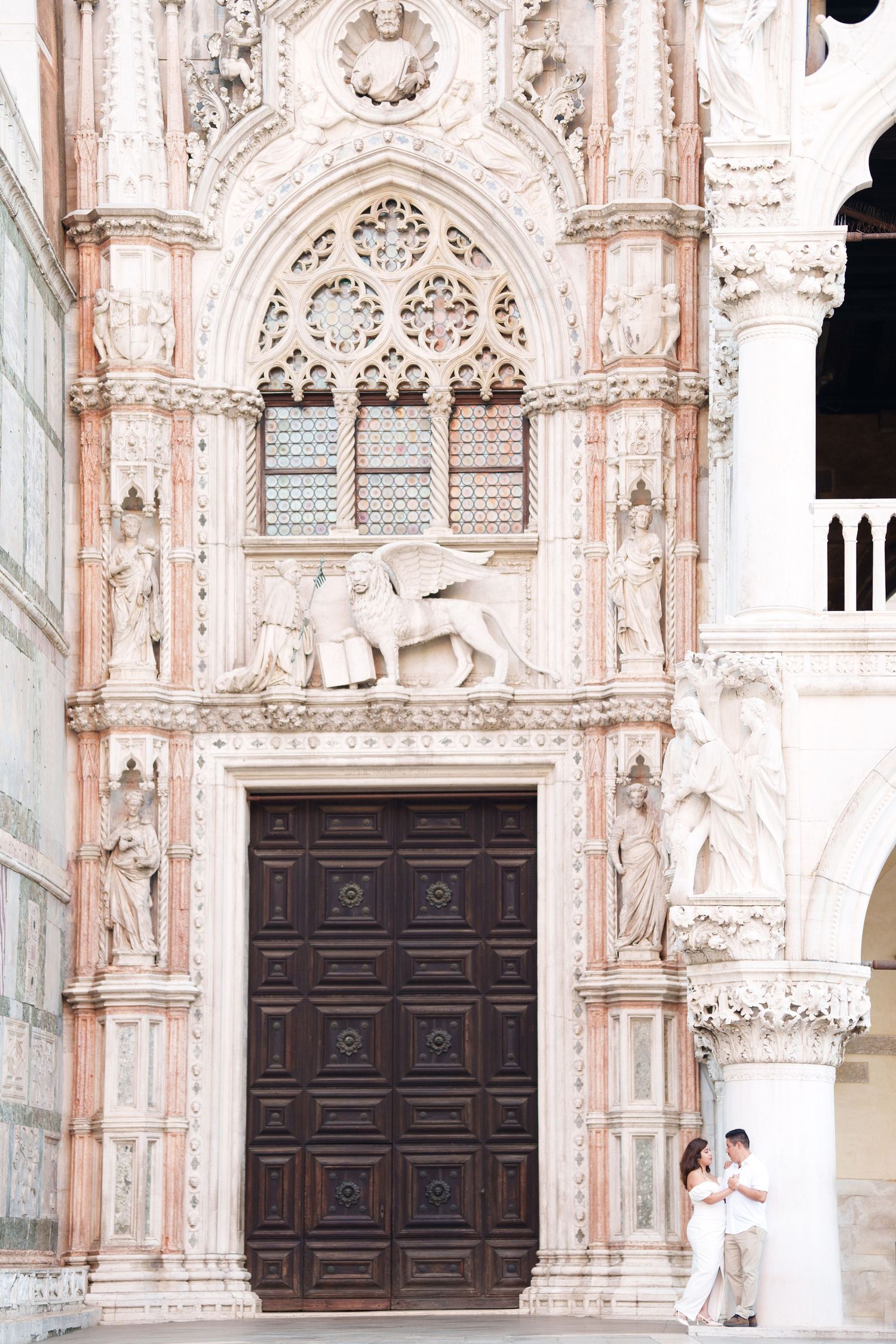 Ornate Gothic doorway of Doge's Palace in Venice with carved stone details and winged lion of Saint Mark above entrance.